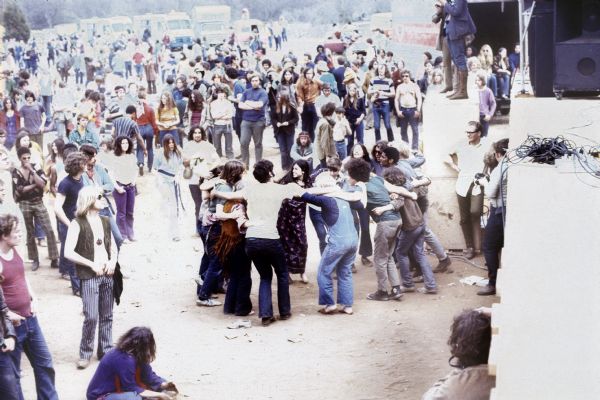 A crowd of people in a circle are dancing at the foot of the stage at the Sound Storm music festival. Other audience members are standing around them watching. (Courtesy of Wisconsin Historical Society)