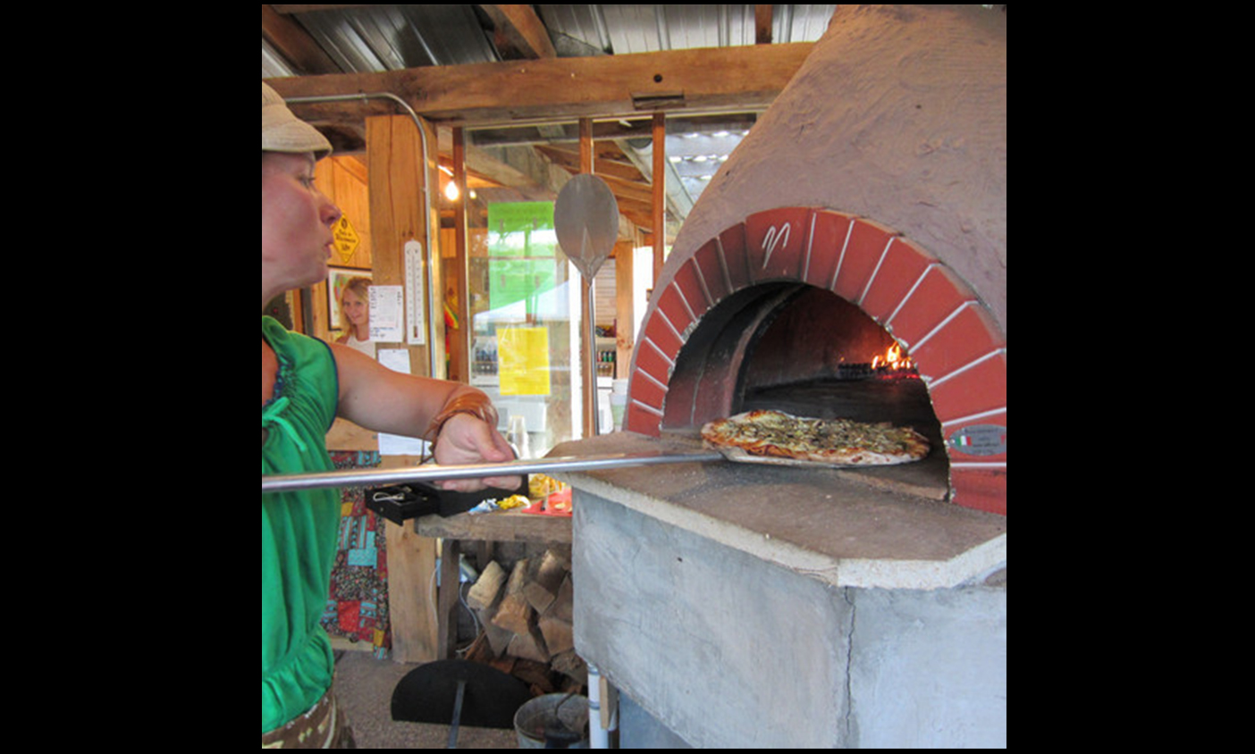 Heather Secrist of Suncrest Gardens Pizza Farm pulls a pizza from her oven. (Photo by Breann Schossow)