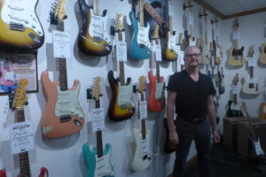 Dave Rogers stands in front of a wall of Fender guitars. These make up some of his private collection at Dave's Guitar Shop in La Crosse, Wisconsin.