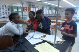 Theisen Middle School students Vanessa Bennett, Landiran Kern, Quendarius Jones, and Ben Graham playing with a radio recorder after talking about race with their teacher.
