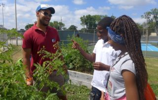 Groundwork Milwaukee's Alex Hagler watches while Young Farmers Amir Washington and Lynnette Maddox try jalapeños from their garden.