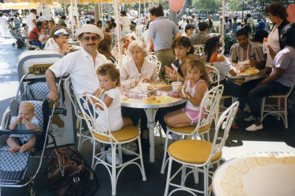 Grandmother, parents and children eat hamburgers and fries al fresco