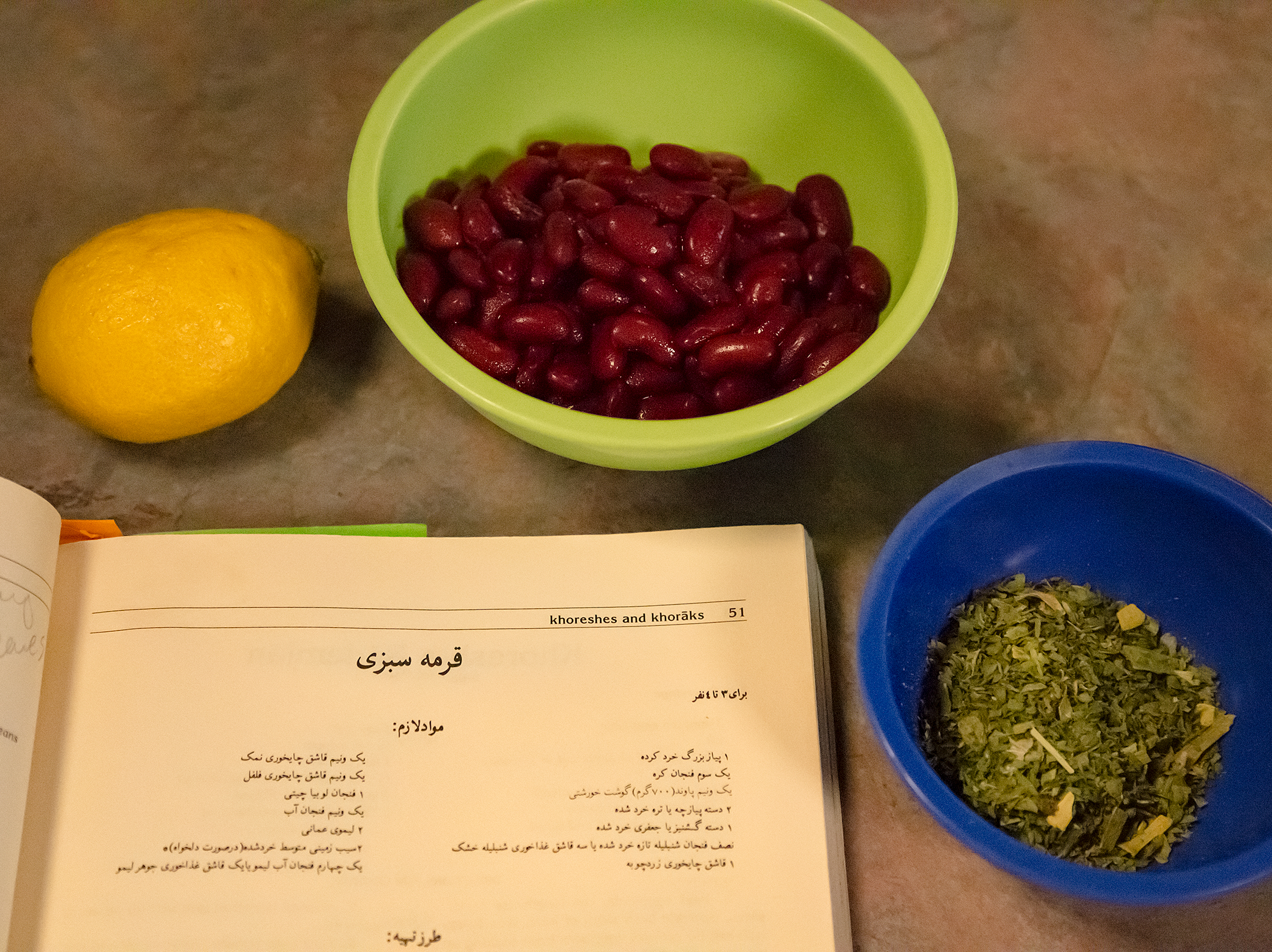 A lemon, kidney beans, minced parsley and a Persian cookbook