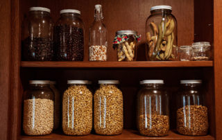 Two shelves of glass jars filled with corn and dried pods