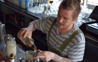 Merchant bar manager Lucas Endres mixes a Breakfast with Petey Pablo cocktail. (Jenny Peek/WPR)