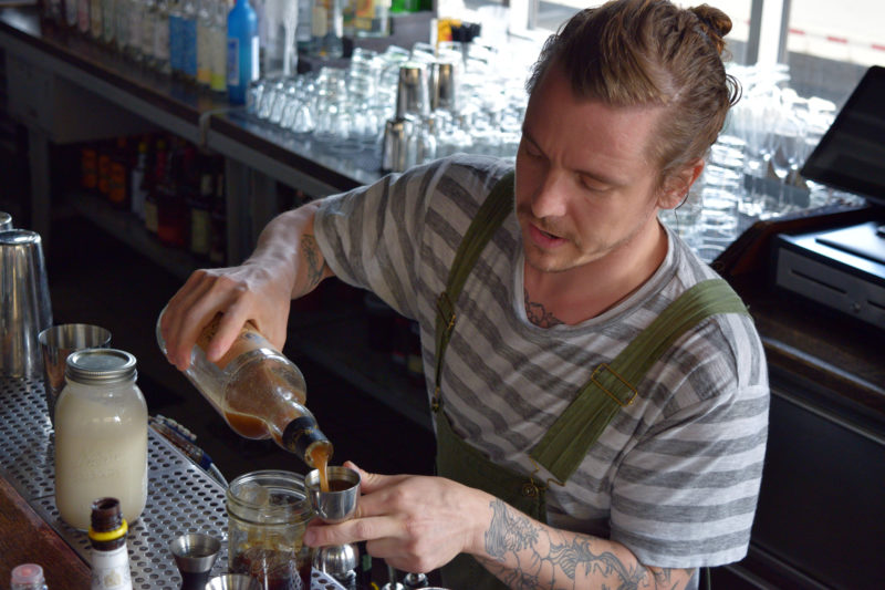 Merchant bar manager Lucas Endres mixes a Breakfast with Petey Pablo cocktail. (Jenny Peek/WPR)