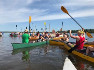 Paddles up and cheers go out as the 2019 PaddleQuest sets off. (Rob Mentzer/WPR)