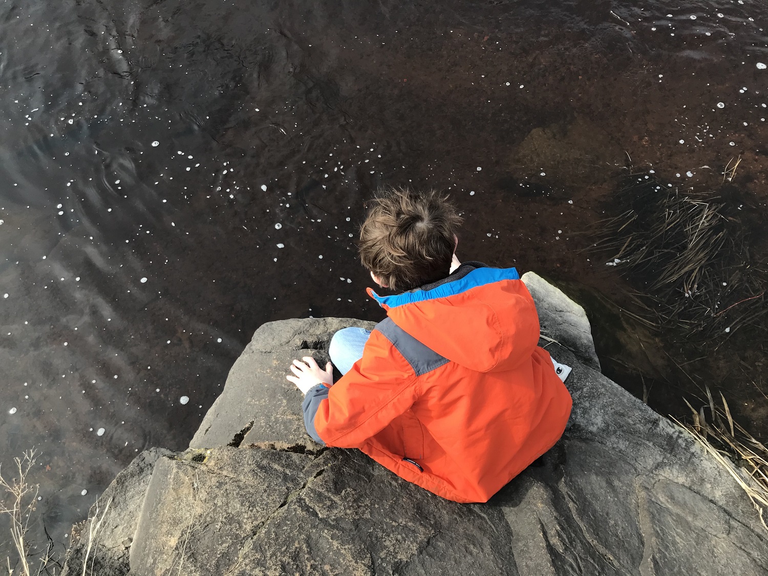 Forrest Mentzer leans over the Wisconsin River. He took a break from a family bike ride to climb on the rocks. (Rob Mentzer/WPR)