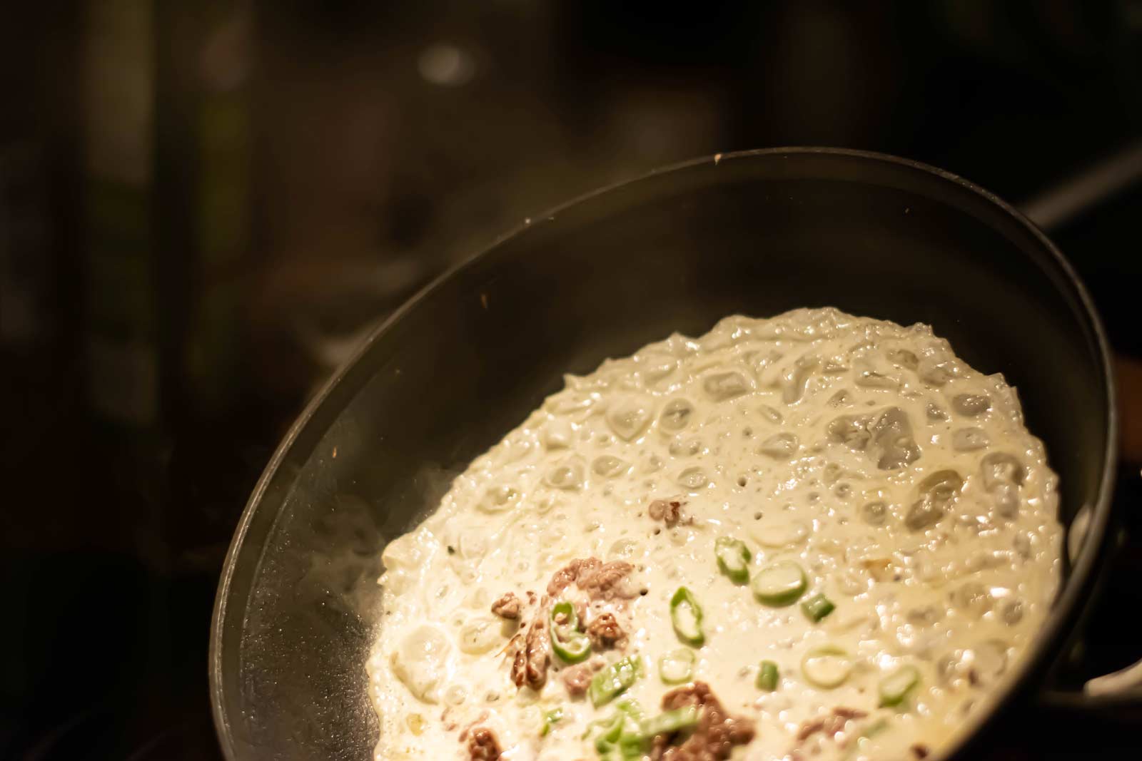 View of fry pan in the middle of cooking a Vietnamese crepe.