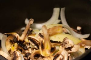 A close-up of sauteing mushrooms and onions