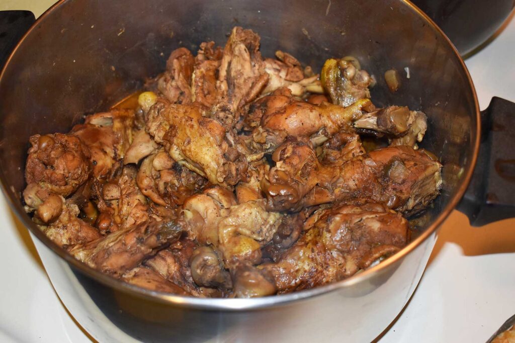 Stainless steel pot filled with jerk chicken