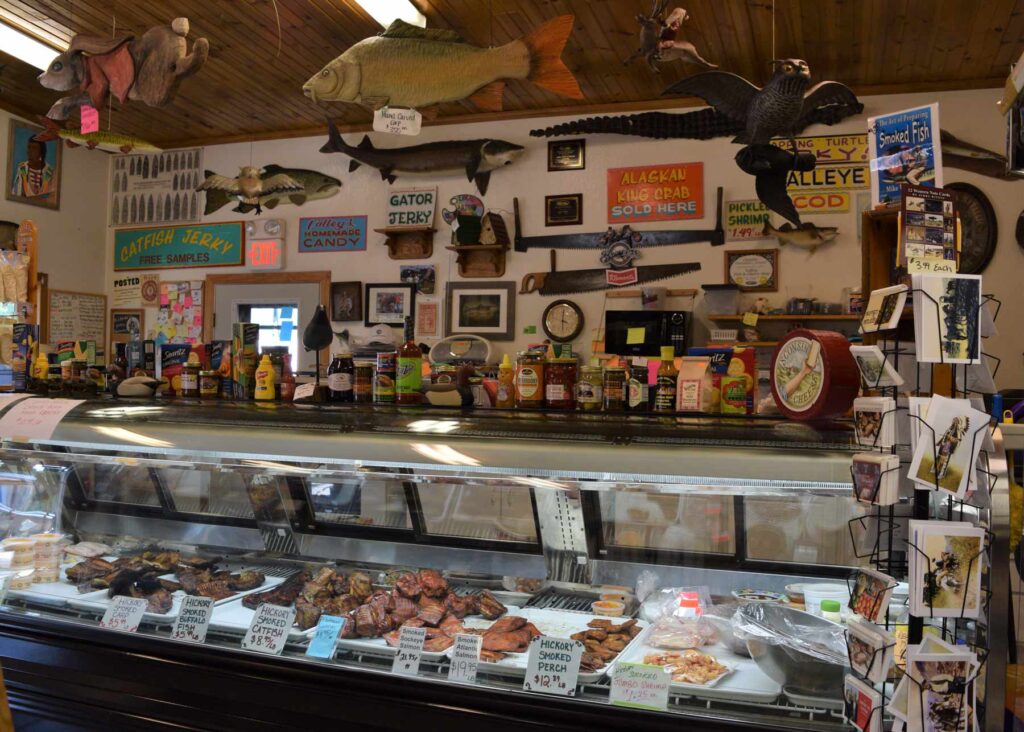 Refrigerated display case. Fish mounts and signs hang on wall above.