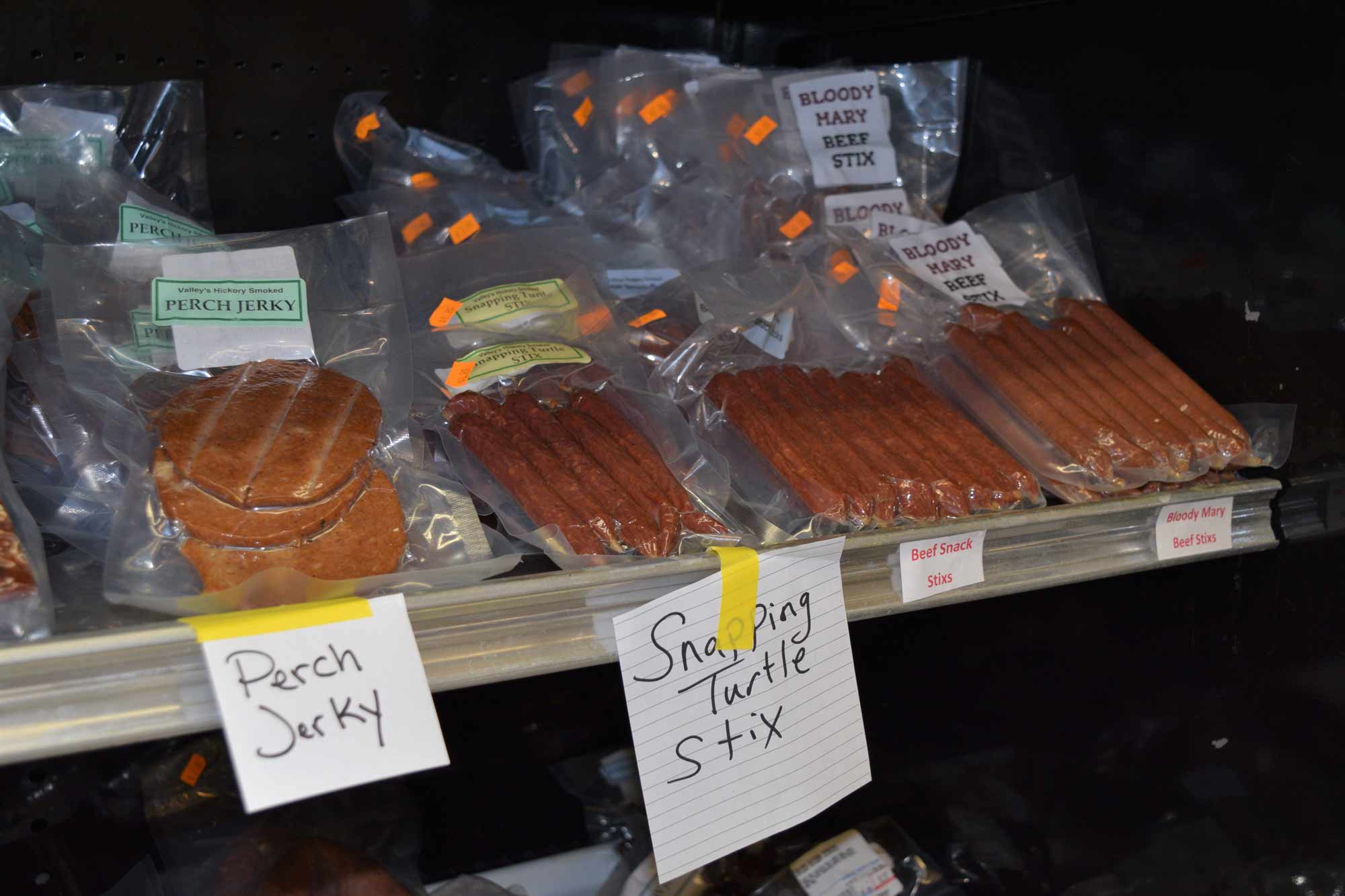 Selection of jerky on store shelf. Handwritten signs. Perch jerky. Snapping turtle stix.