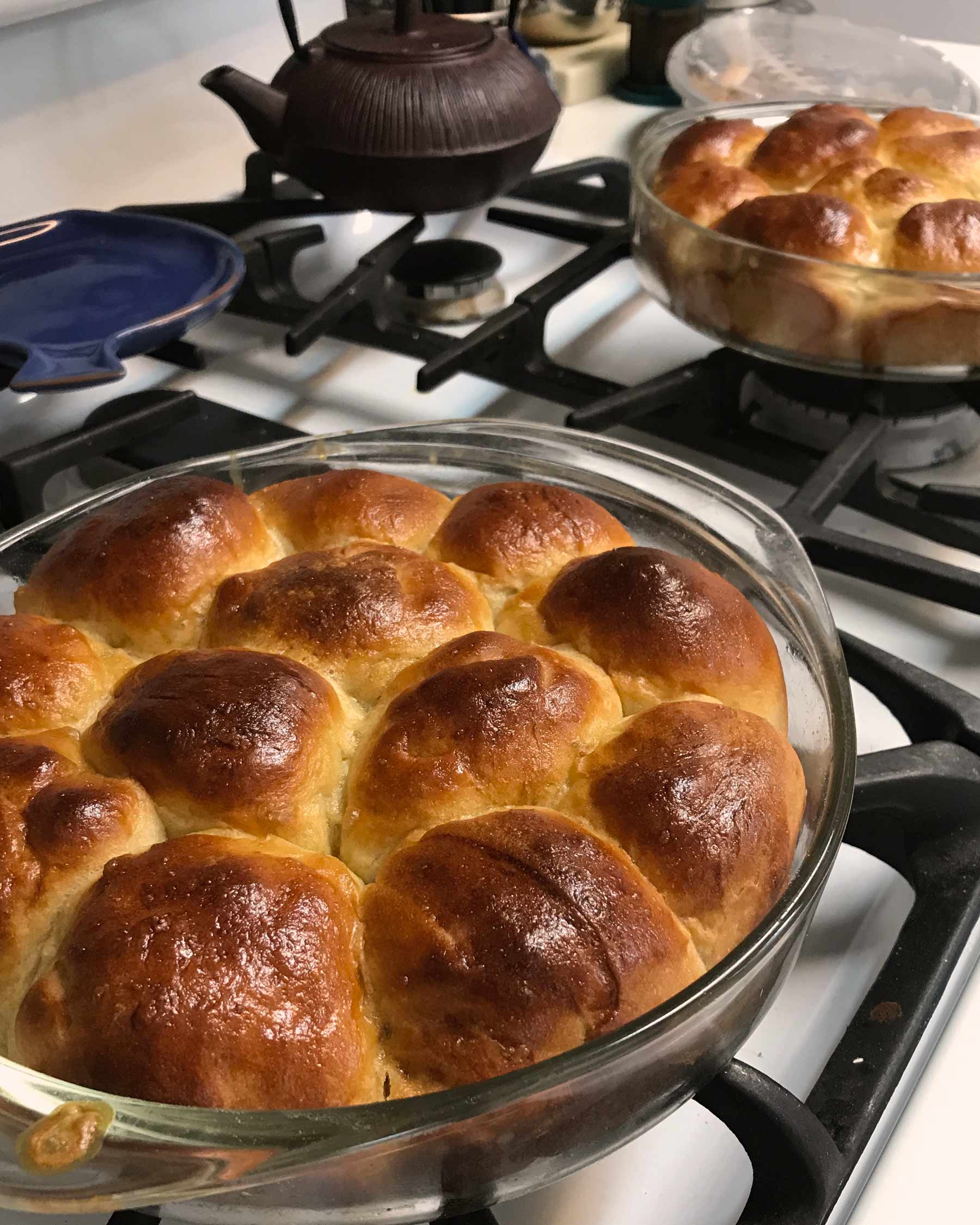 Pans of dinner rolls rest on top of stove.