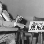 Leonard Schmitt, independent Republican candidate for the U.S. Senate, holds a copy of The McCarthy Record and points to an empty chair with a sign showing the seat reserved for his opponent, Joseph R. McCarthy, to debate the issues with him. (Courtesy of the Wisconsin Historical Society)