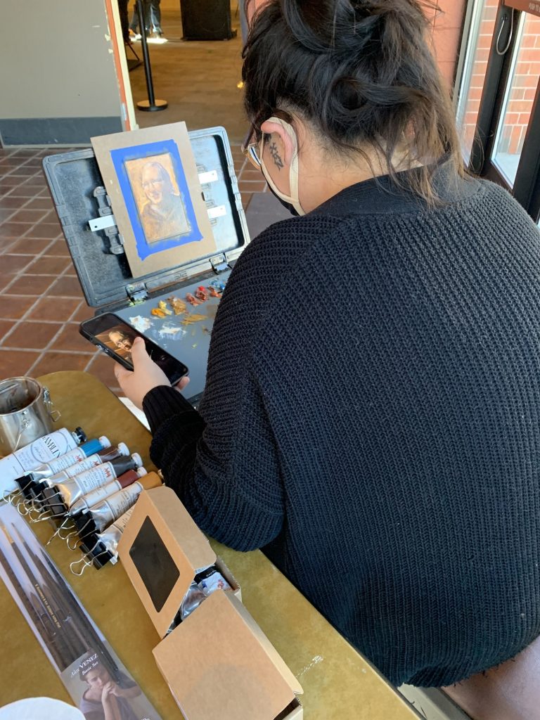 Sonia Vasquez paints a portrait at the Rahr-West Art Museum as part of the "Portrait of Manitowoc" project. (Megan Hart/WPR)