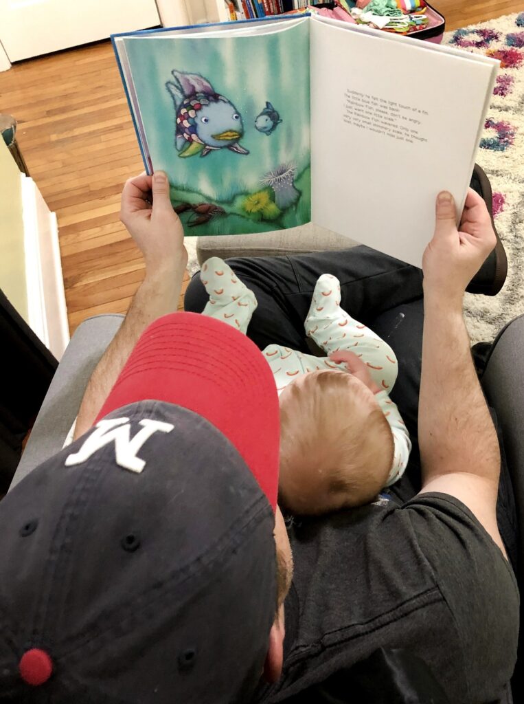 Joshua Grube reads “The Rainbow Fish” to Magnolia Grube in her bedroom before bed at their home in Janesville, Wis. in March 2021. (Andrea Anderson/WPR)