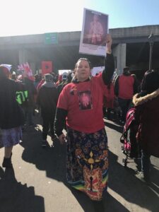 Lorraine Shooter at a march wearing a shirt and holding a sign with Rae Elaine Tourtillot on it. (Courtesy of Andrea Lemke-Rochon)