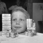 Child posing with polio vaccine bottles and boxes. (Courtesy of Wisconsin Historical Society)