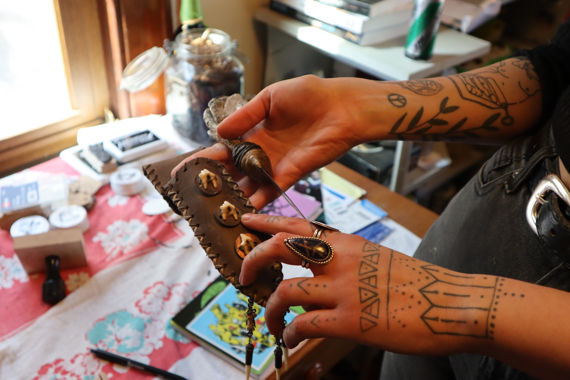 Lisa Lauren, the owner, artist and silversmith of Kettle Black Silver Co., shows a knife sheath she made that's adorned with coyote teeth. (Steven Potter/WPR)