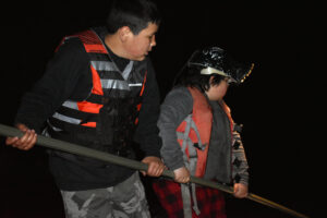 Ganebik Johnson, 11, helps his cousin Liam Armstrong, 9, while spearfishing on May 7, 2022. (Danielle Kaeding/WPR)