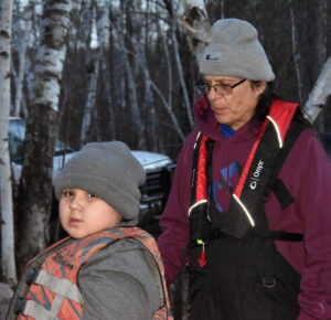 Ojibwe language and cultural teacher Wayne Valliere stands next to Liam Armstrong, 9, before tribal youth go spearfishing on May 7, 2022. (Danielle Kaeding/WPR)