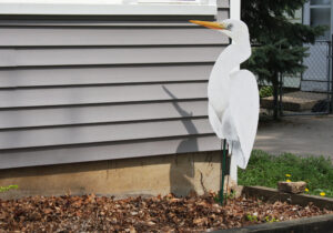 A wooden egret stands on one leg.