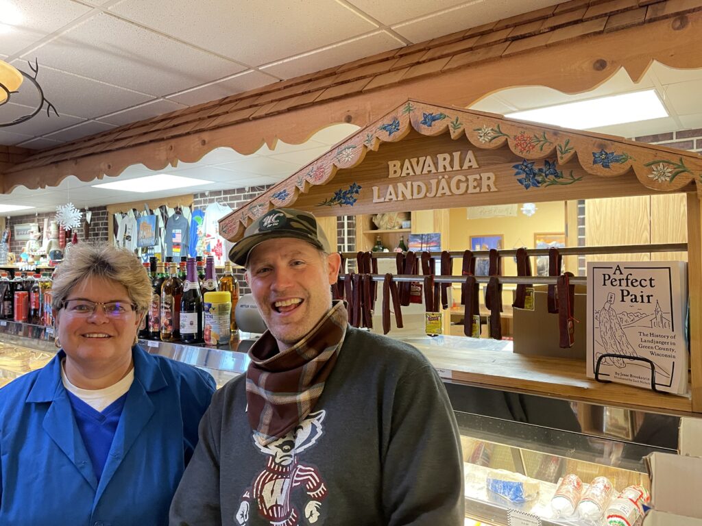 Judy Cottrell and Jesse Brookstein pause in front of the Landjager display case and Brookstein's book at Bavaria Sausage in Madison (Brad Kolberg/WPR)