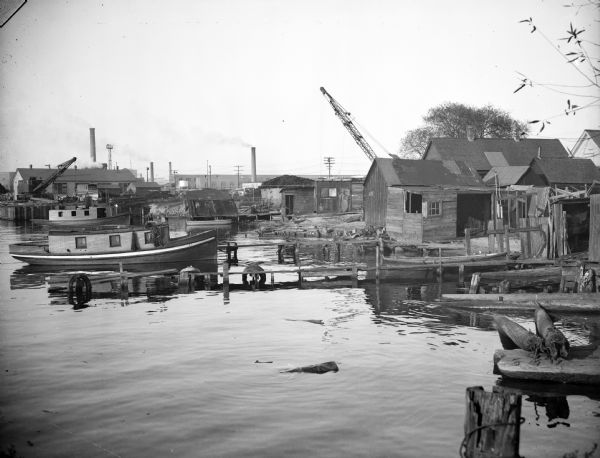 Docks and shanties at Jones Island, with smokestacks and cranes in the background.