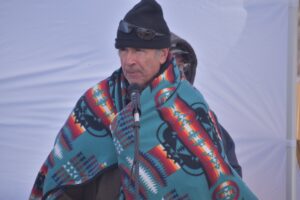 Oneida Nation tribal member Paul DeMain emcees the Mooningwanakaaning Minis Inter-Tribal Snow Snake Festival as tribal and nontribal members compete on Feb. 11, 2023. (Danielle Kaeding/WPR)