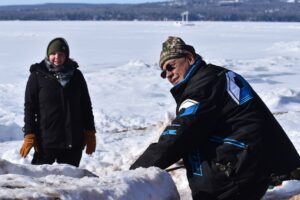 Frank Sprague with the Gun Lake Band of Pottawatomi Indians lines up his snow snake on the track on Feb. 11, 2023. (Danielle Kaeding/WPR)