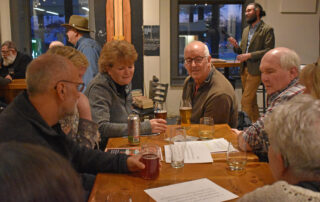 A small group brainstorms the answer to a trivia question at the Neenah Public Library’s Short Story Night in mid-March 2023. (Joe Schulz/WPR)
