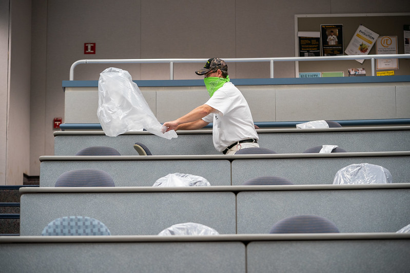 A UW-Oshkosh custodian places a plastic bag over a chair in a lecture hall on campus. To promote social distancing, every other chair in the hall was covered in plastic. (Courtesy of UW-Oshkosh)