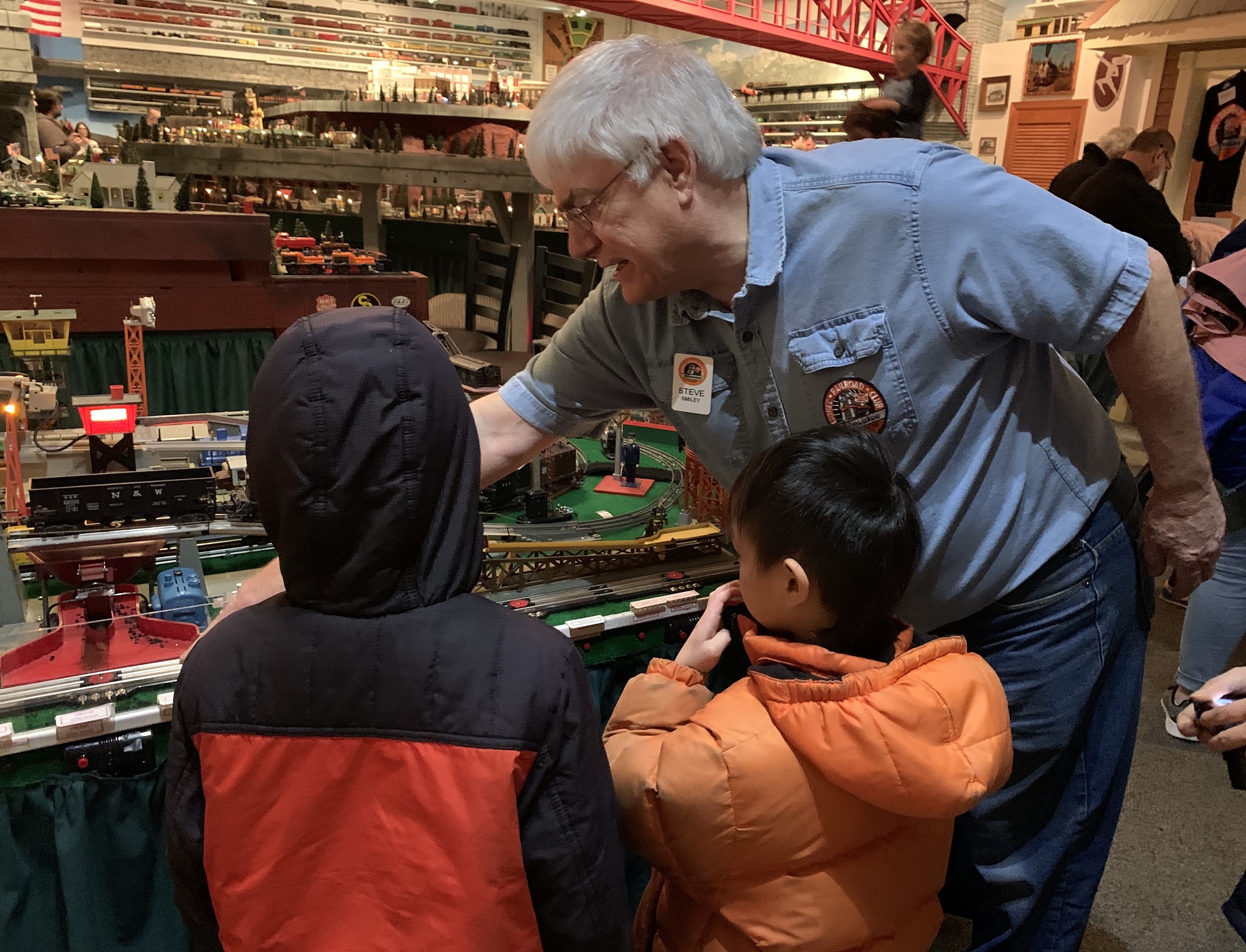 Lionel Railroad Club President Steve smiley and shows trains to the Wu siblings of New Berlin, Wisconsin. (Photo by Jane Hampden)