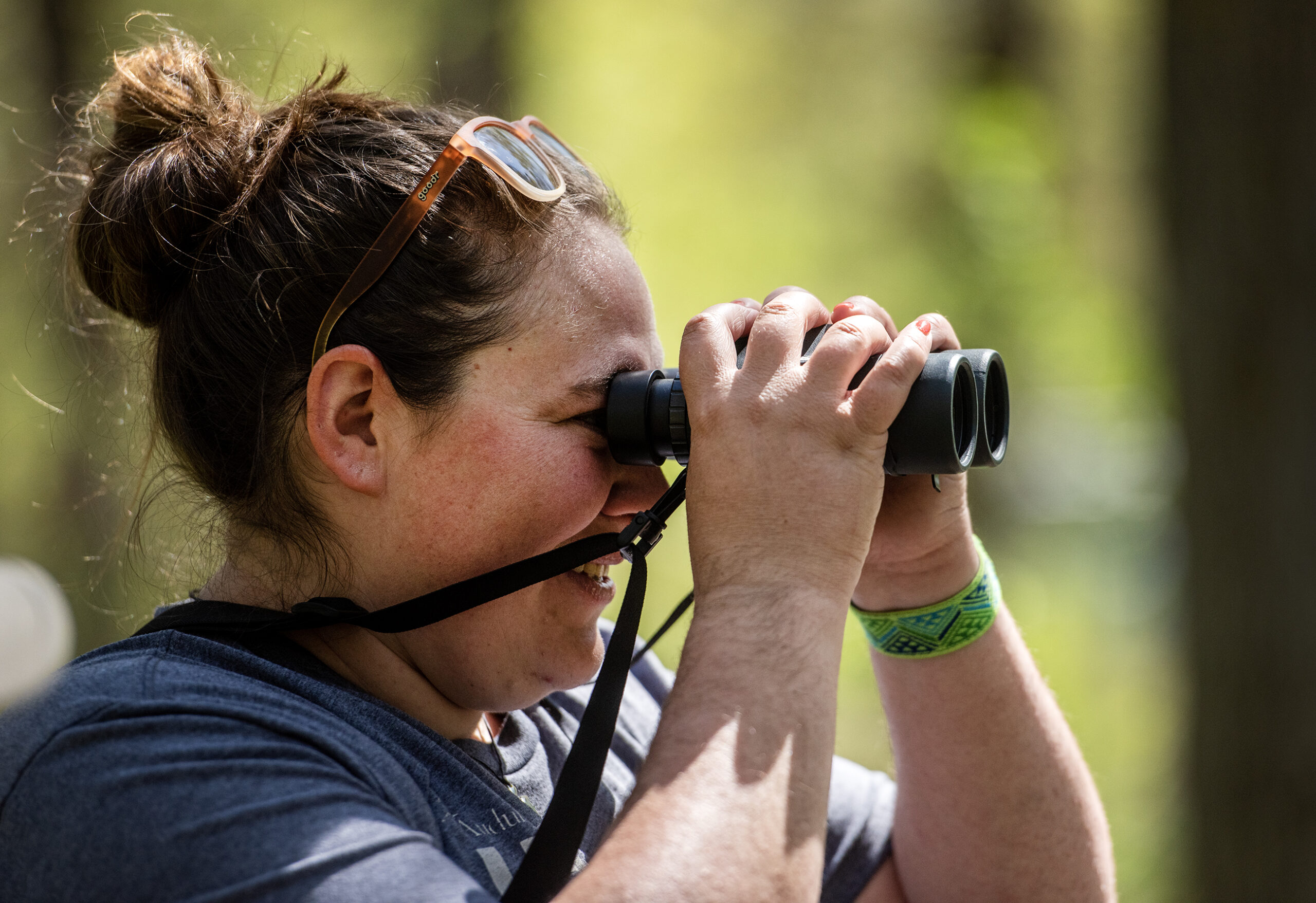 Kari Hagenow, a land steward and conservation project manager at The Nature Conservancy in Wisconsin, uses binoculars to find birds Wednesday, May 10, 2023, at Wyalusing State Park in Bagley, Wis. (Angela Major/WPR)