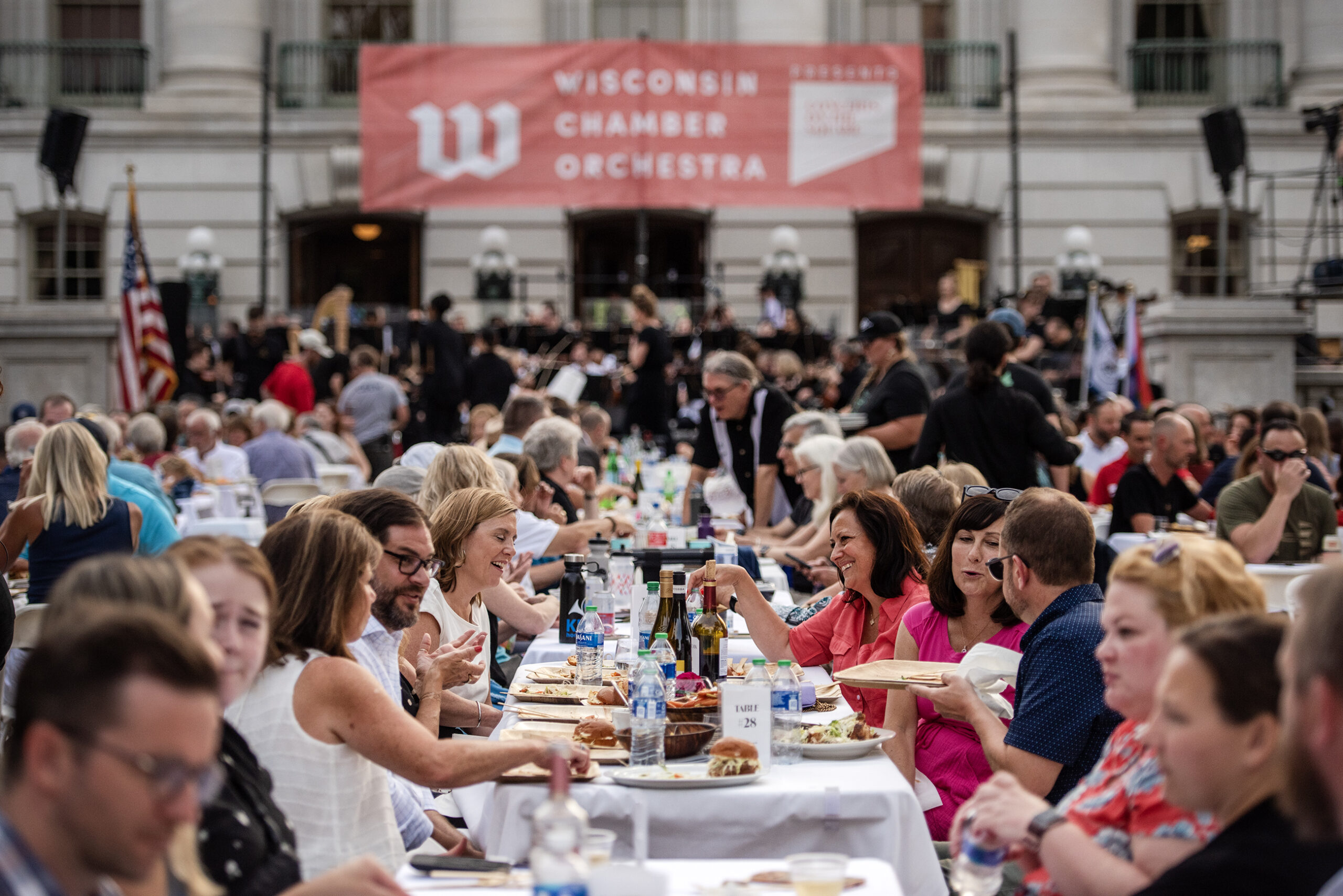 Attendees enjoy food and wine as the Wisconsin Chamber Orchestra plays Wednesday, July 19, 2023, at the Wisconsin State Capitol in Madison, Wis. (Angela Major/WPR)
