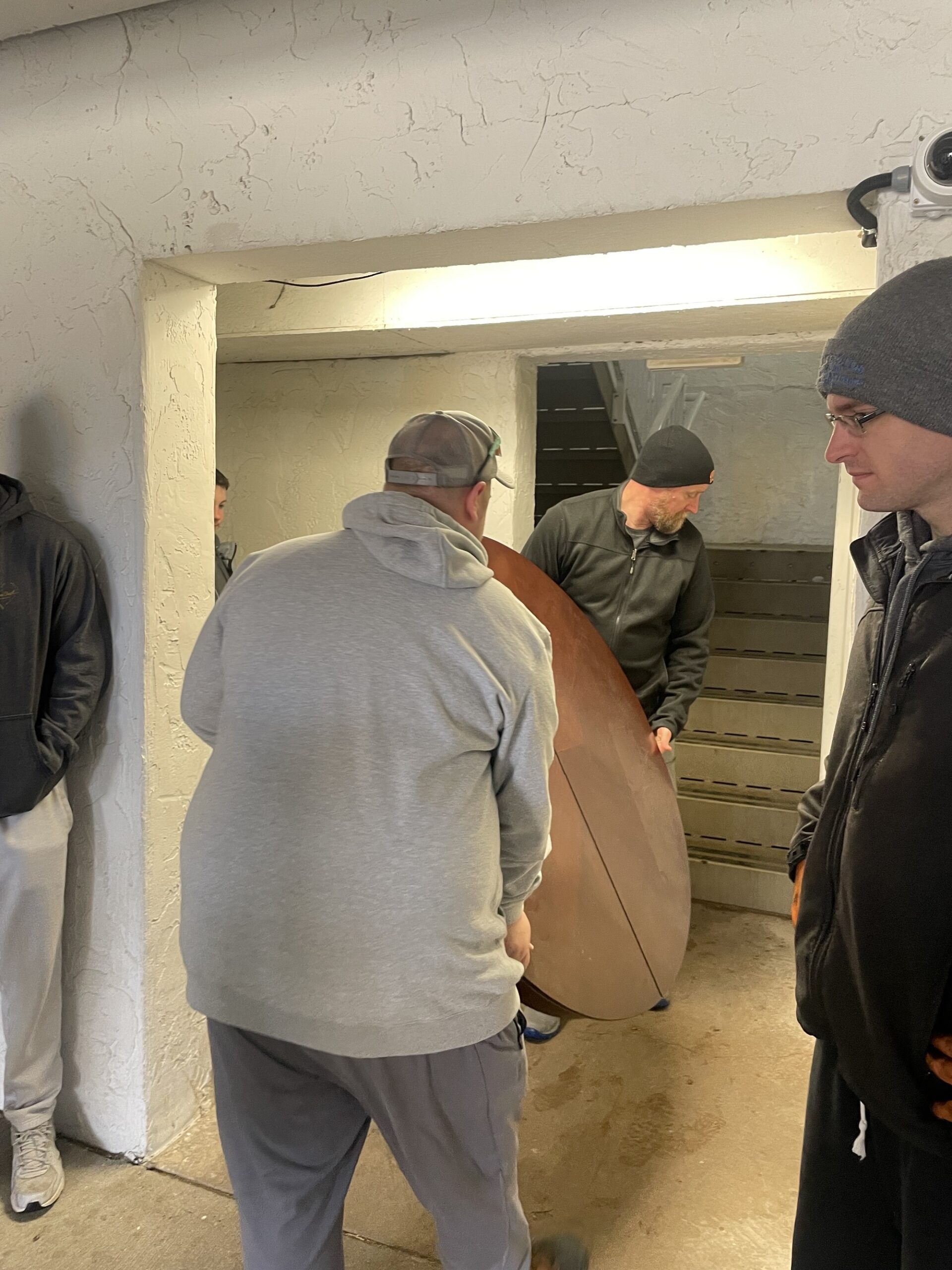Volunteers with Felicia’s Donation Closet, a nonprofit that furnishes homes for survivors of domestic abuse, haul a table up a flight of stairs to help make a family’s new apartment feel like home. (Gaby Vinick/WPR)