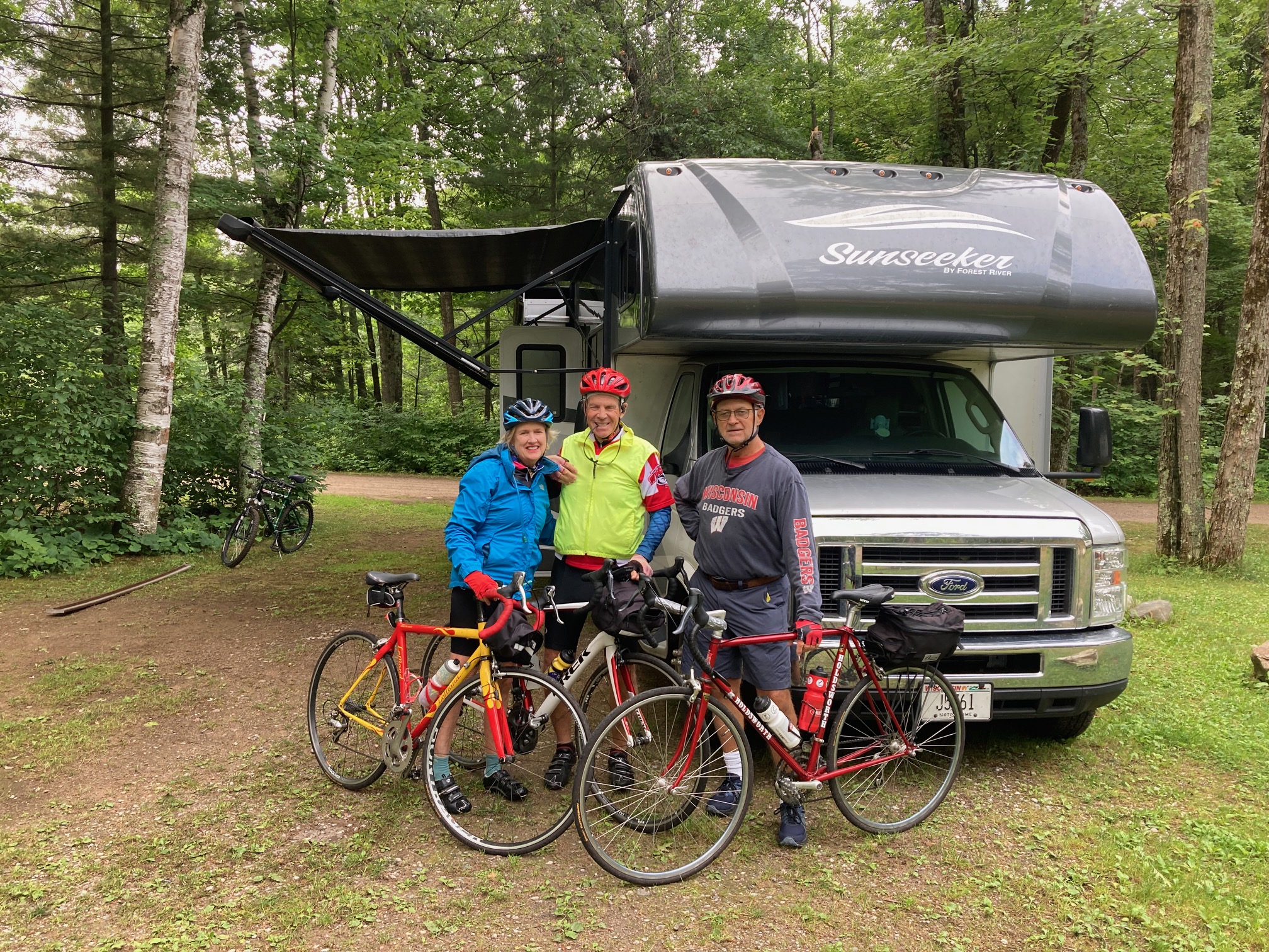 Emily Blaskey, Mark Blaskey, and Nick Schmelter next to their RV they rested in during their bike ride from Wisconsin to the Canadian border in July 2023. (Photo by Andrea Kubishak)
