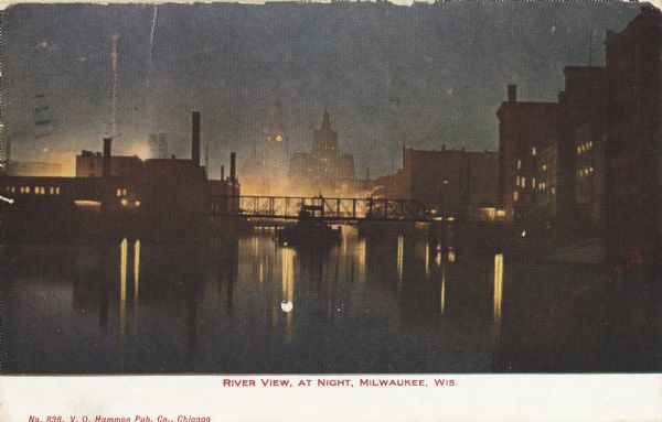 Railroad bridge over river and buildings at night in Milwaukee, Wisconsin circa 1909. In the distance is a building with a clock tower. Caption reads: "River View, at Night, Milwaukee, Wis." (Courtesy of Wisconsin Historical Society)