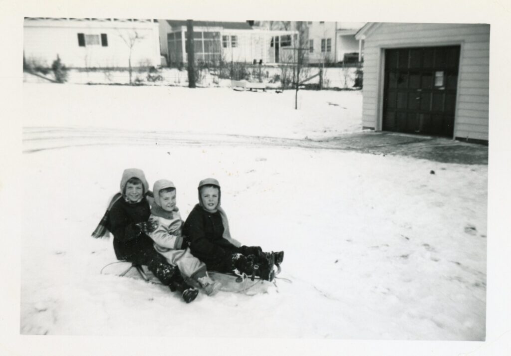 Chris Thomas, on the back of the sled, with her brothers. They're near their garage poised to go downhill on what is now Westmorland Blvd. towards its end at Westmorland Park in Madison, Wisconsin. (Courtesy of Alexandra Salmon)