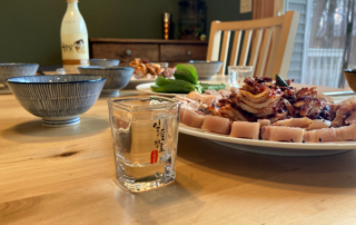 Soju sits in a shot glass with the plated Bossam kimchi and Sooyook set on the table.