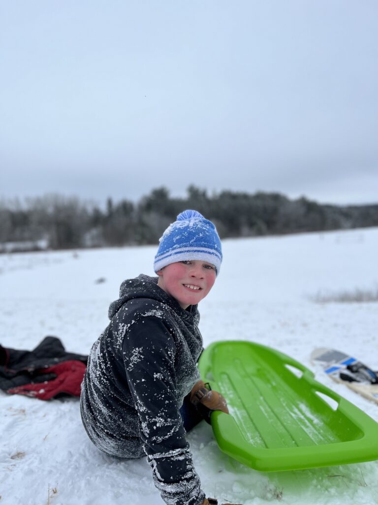Beau Quinn switches between his sled and snowboard on a snowy day in Stockton Park, Wisconsin. (Photo by Jill Sisson Quinn)