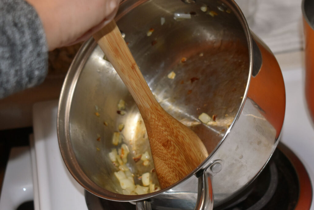 Sarah Gordon Altiman sautés onions on the stove as part of a recipe for Potawatomi-style corn soup on Dec. 21, 2023. (Danielle Kaeding/WPR)