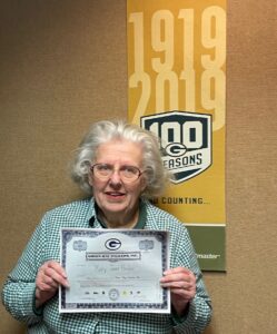Mary Jane Herber poses with a mock Green Bay Packers stock certificate at the Brown County Library. She's been a shareholder since the 1990s and has been working as a librarian in Brown County since 1971. (Courtesy of Mary Jane Herber)