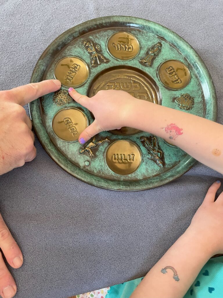 Mark E. Griffin points out to his daughter the beitza, or roasted egg, symbolizing spring, rebirth, and the cycle of beginnings and endings in life on the family's seder plate. (Photo by Melissa Motew)