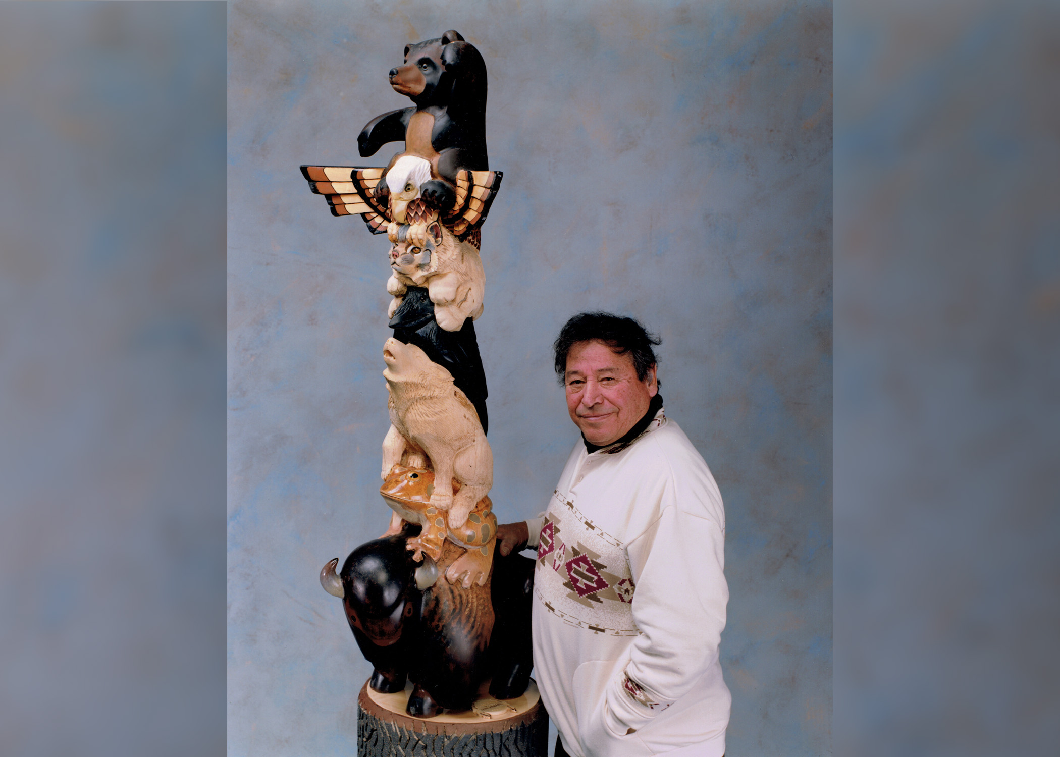 Artist Harry Whitehorse of Monona, Wisconsin next to a clan pole he carved from basswood. It's currently on display at the WHEDA building in Madison, Wisconsin. (Courtesy of Deb Whitehorse)