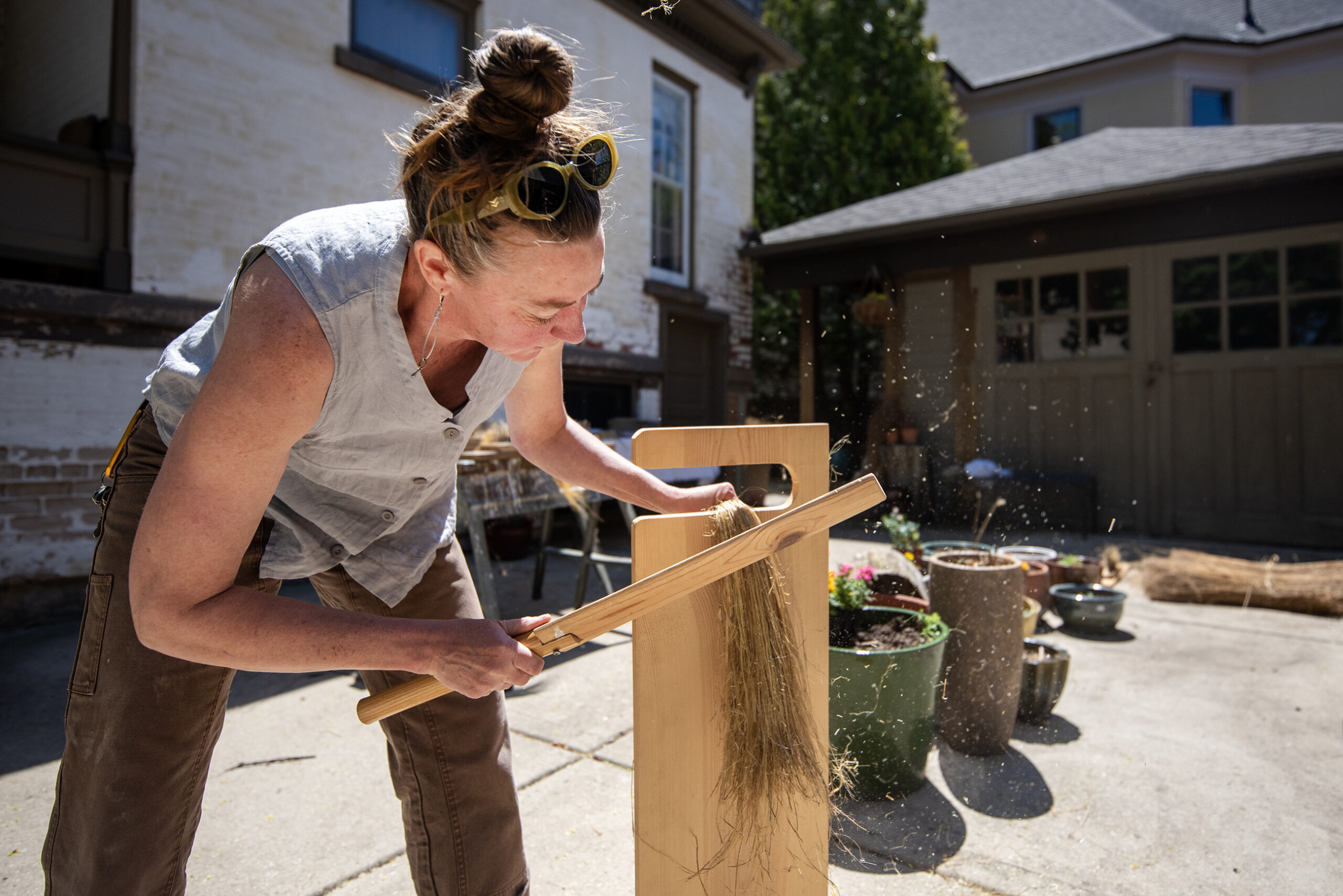 Leslie Schroeder scutches flax, part of the process of breaking it down, on Thursday, May 8, 2025, in Madison, Wis. <i>Angela Major/WPR</i>